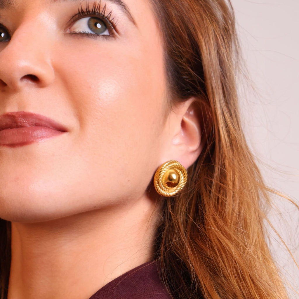 Classic gold stud earrings worn by model in an elegant close-up portrait
