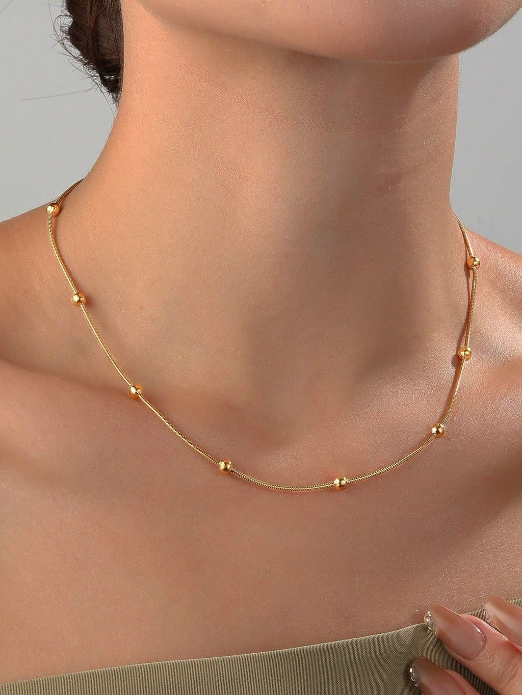 Gold beaded chain necklace worn on the neck, showing fit and length
