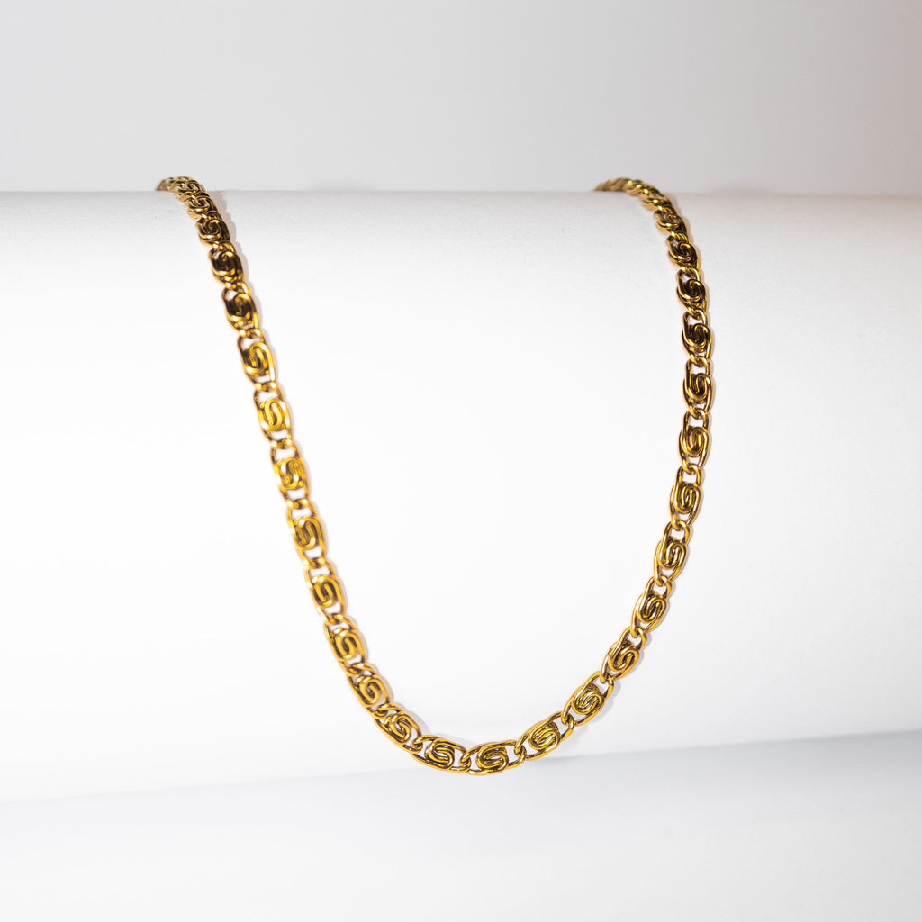 Gold chain necklace with sculptural interlocking links on white background

