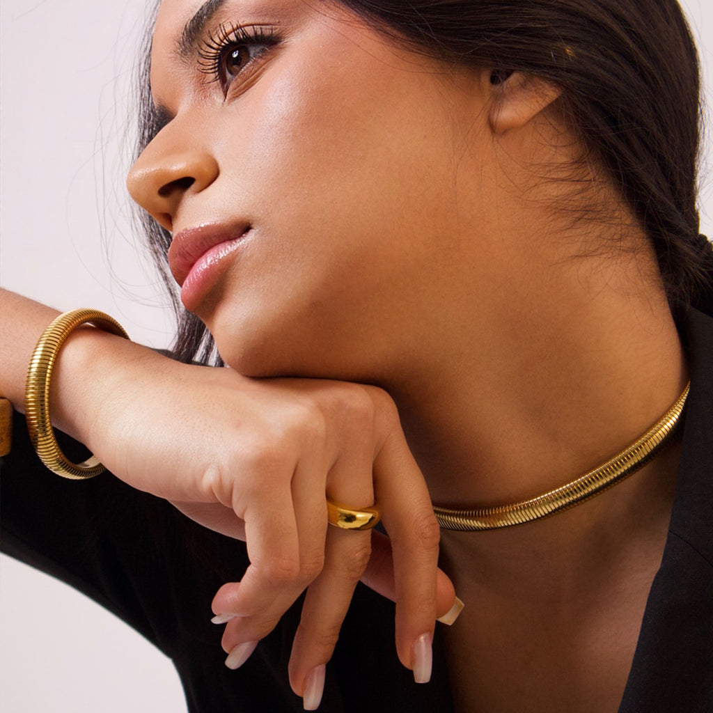 Gold ribbed bangle bracelet with a sleek minimalist finish on a white background
