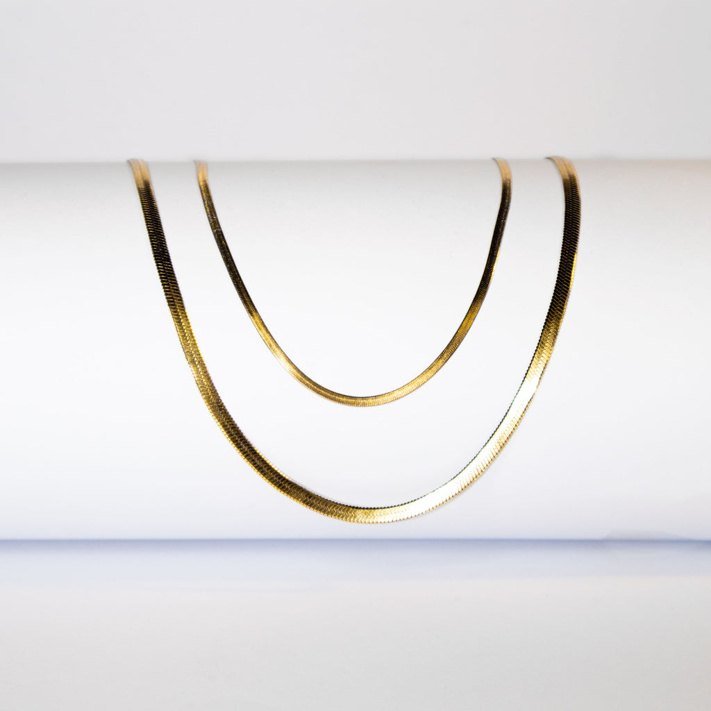 Gold snake chain necklace with flat polished surface displayed in double layer
