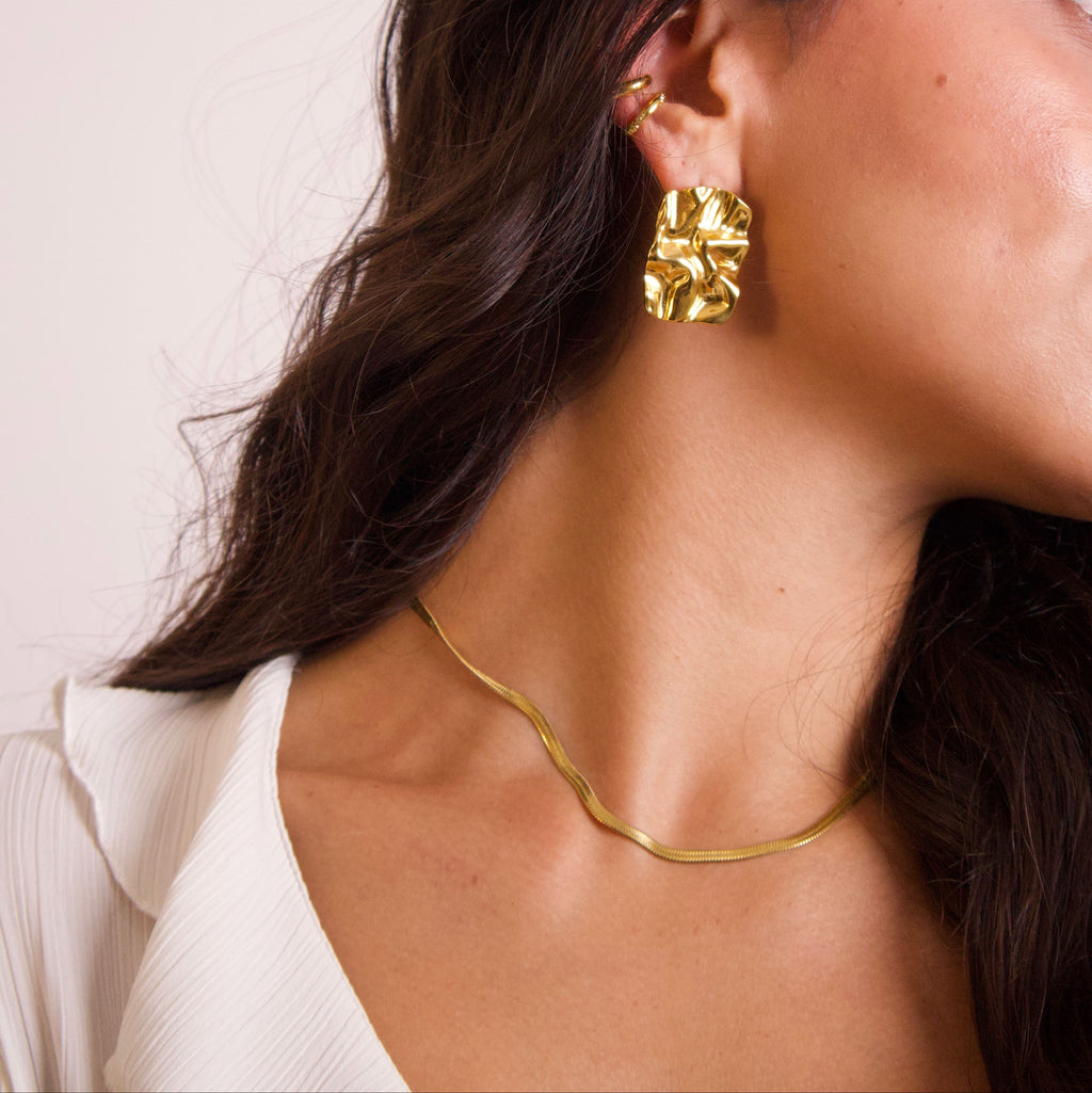 Close-up of flat gold snake chain necklace with smooth reflective finish
