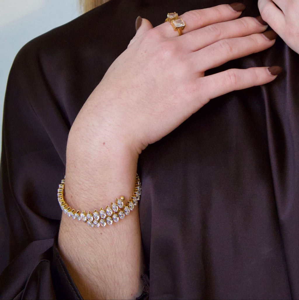 Gold bracelet featuring a structured row of marquise-cut clear crystals
