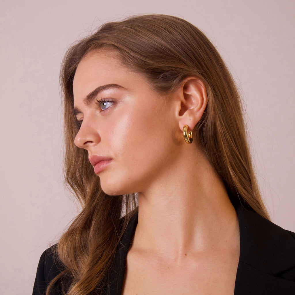Minimal gold hoop earrings worn on ear in side profile portrait
