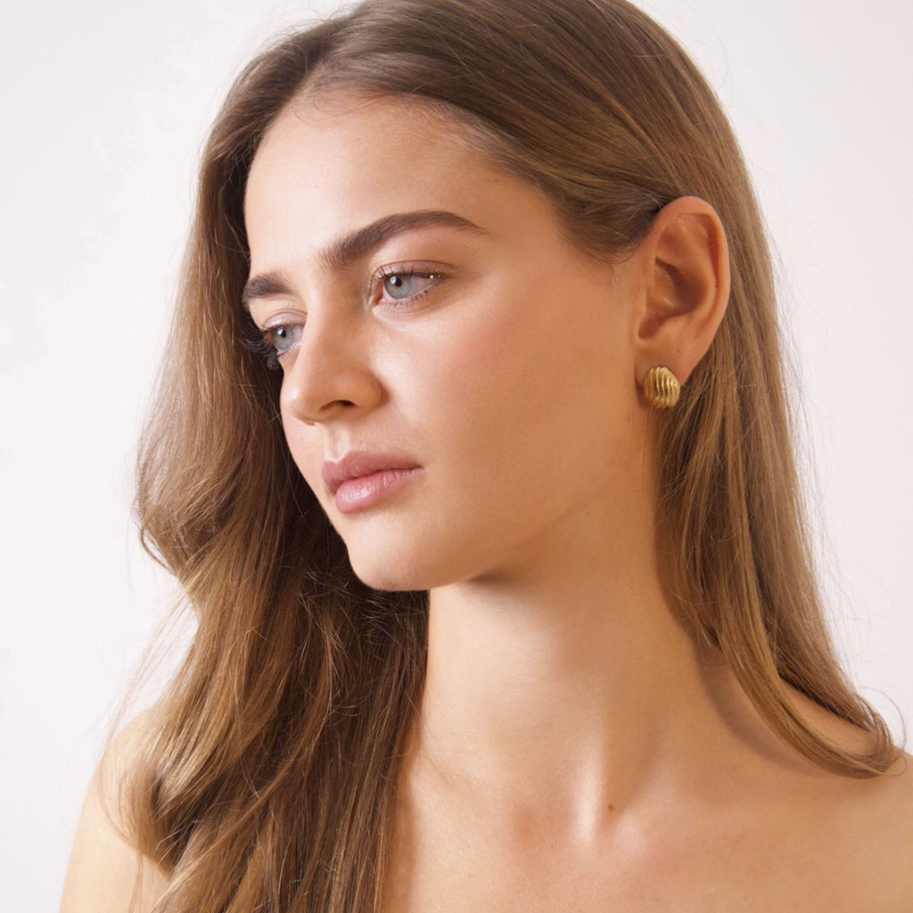 Model wearing minimalist gold stud earrings with a timeless elegant design
