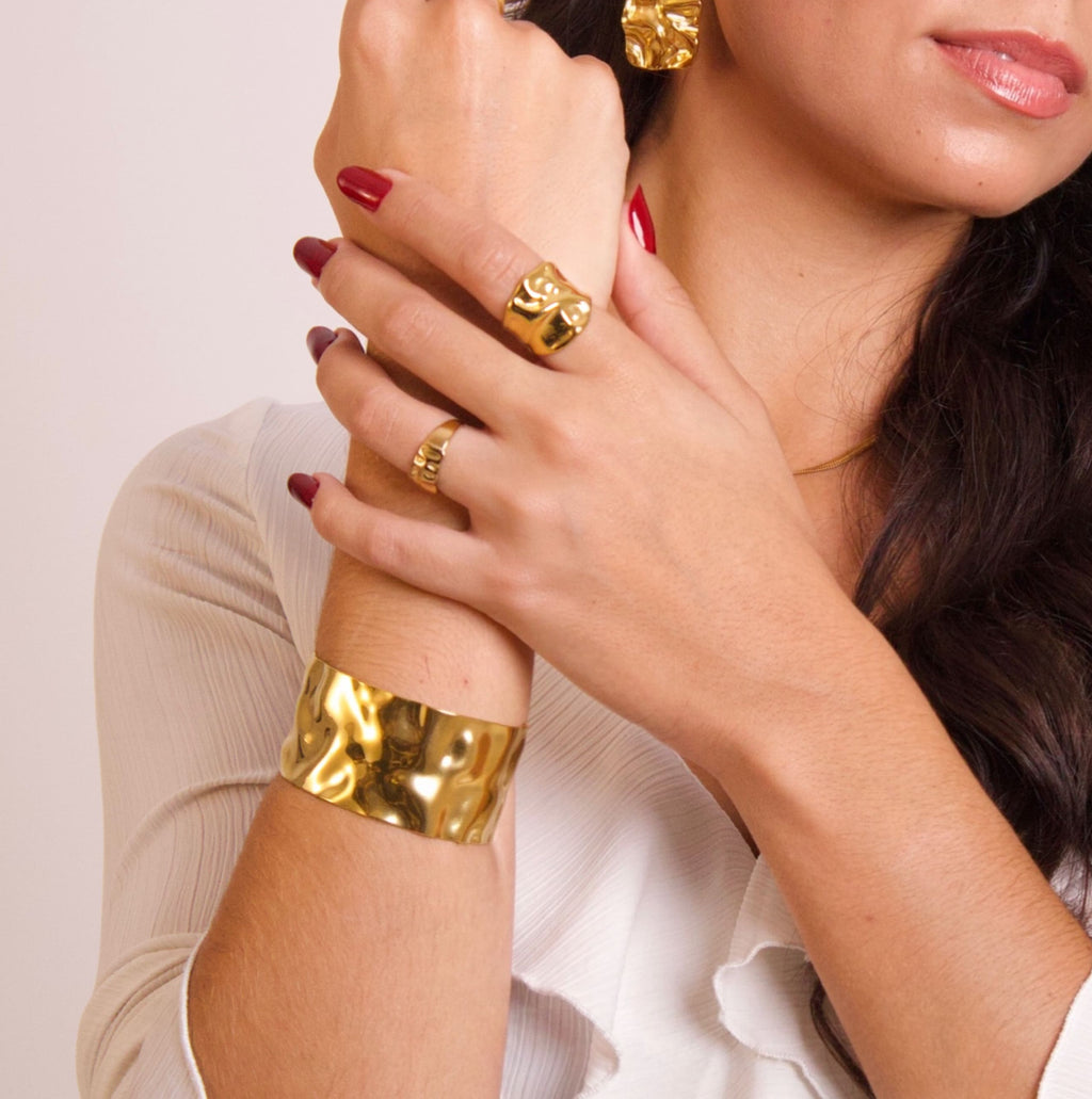 Organic gold statement ring with sculptural irregular texture on white background
