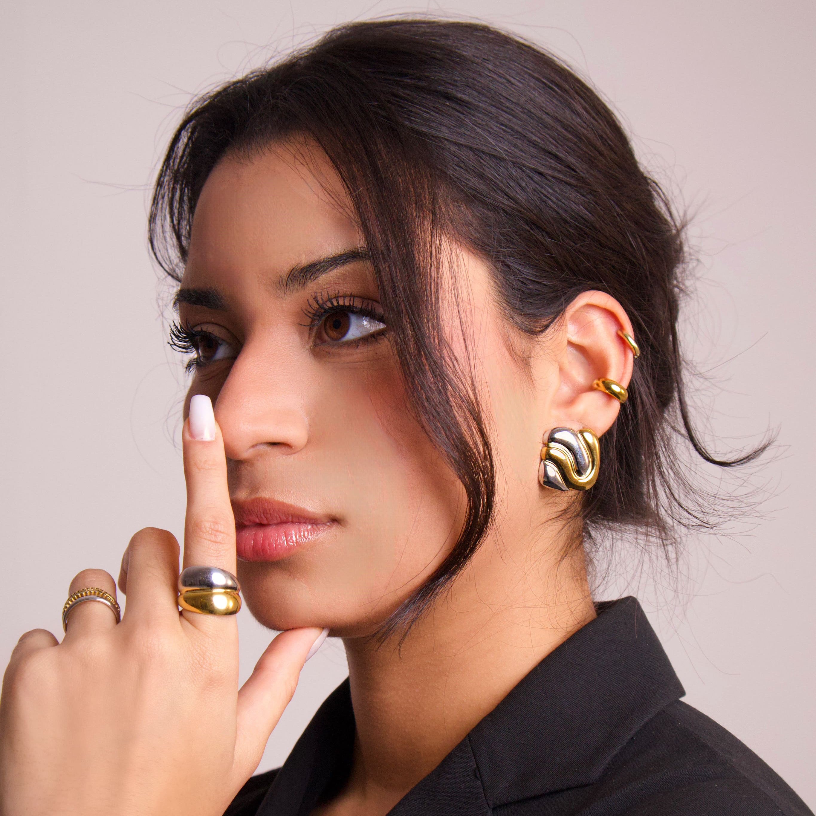 Model wearing sculptural two-tone gold and silver statement earrings with a modern organic design
